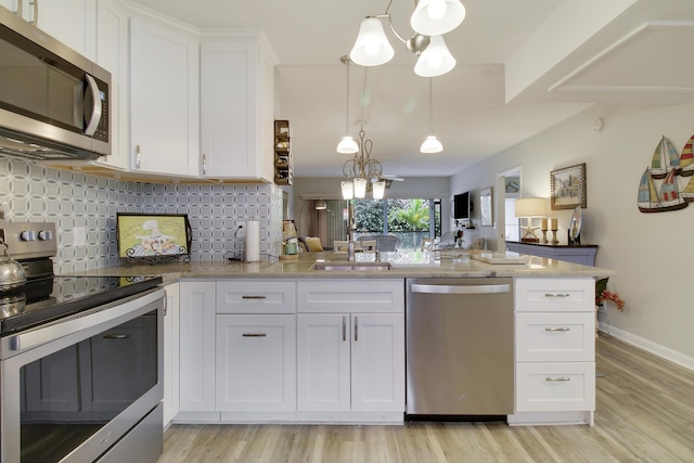 kitchen featuring backsplash, light wood-style flooring, appliances with stainless steel finishes, white cabinetry, and a sink