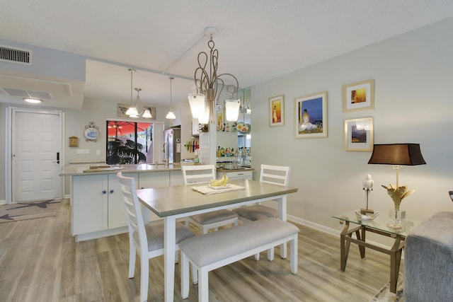 dining area with visible vents, light wood-style flooring, and baseboards