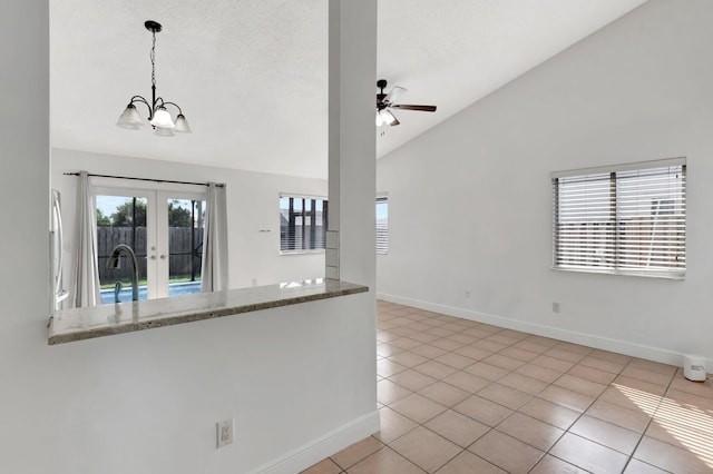 5598 Pebble Brook Ln, Boynton Beach, FL 33472 - kitchen featuring light tile patterned floors, ceiling fan with notable chandelier, vaulted ceiling, light stone countertops, and decorative light fixtures