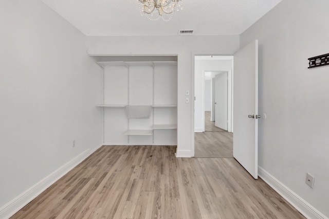 5598 Pebble Brook Ln, Boynton Beach, FL 33472 - unfurnished bedroom with an inviting chandelier, light wood-type flooring, visible vents, and baseboards
