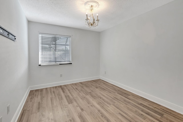 5598 Pebble Brook Ln, Boynton Beach, FL 33472 - unfurnished room with light wood-style flooring, a textured ceiling, baseboards, and a notable chandelier
