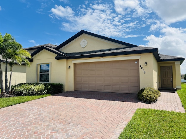 ranch-style home featuring decorative driveway, an attached garage, and stucco siding