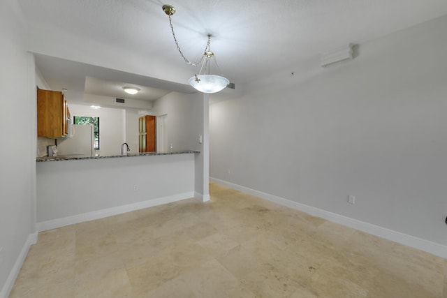 6705 Coral Lake Dr Unit 6705, Margate, FL 33063 - kitchen featuring brown cabinetry, freestanding refrigerator, pendant lighting, baseboards, and dark stone counters