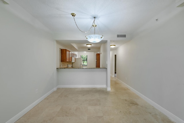 6705 Coral Lake Dr Unit 6705, Margate, FL 33063 - kitchen with brown cabinets, freestanding refrigerator, decorative light fixtures, dark stone counters, and baseboards