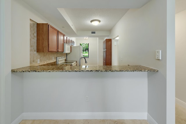 6705 Coral Lake Dr Unit 6705, Margate, FL 33063 - kitchen featuring white appliances, a peninsula, stone countertops, and brown cabinetry