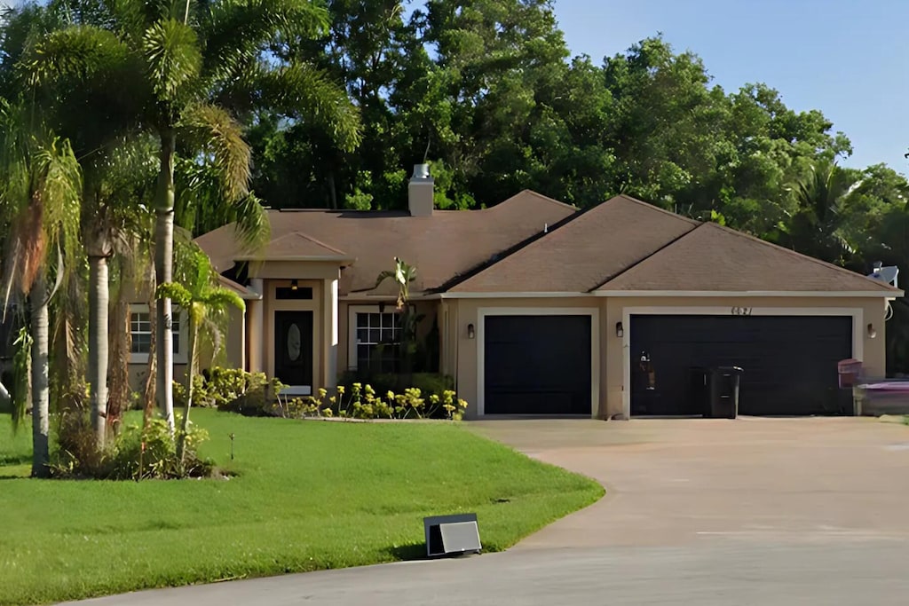 view of front of home featuring a garage, driveway, stucco siding, a chimney, and a front yard