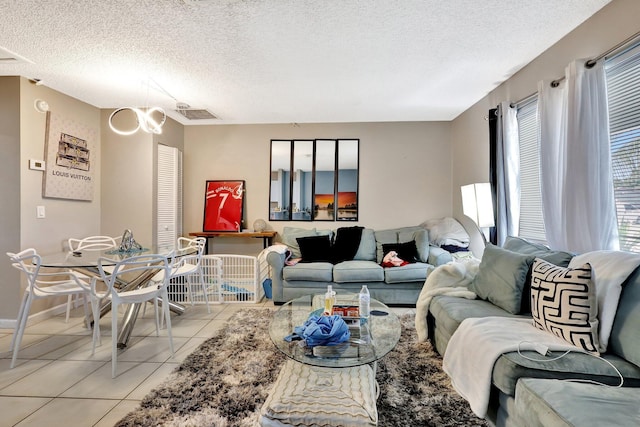 living room featuring visible vents, light tile patterned flooring, a textured ceiling, and baseboards