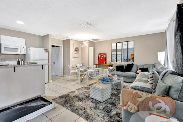 living room featuring light tile patterned floors, baseboards, visible vents, and a textured ceiling