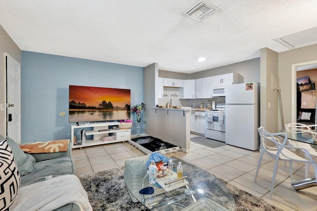 living area with a textured ceiling, light tile patterned flooring, and visible vents