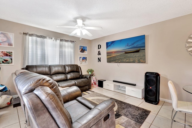 living area with ceiling fan, a textured ceiling, baseboards, and light tile patterned floors