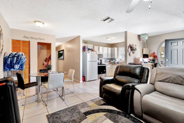 living area with light tile patterned floors, ceiling fan, visible vents, and a textured ceiling