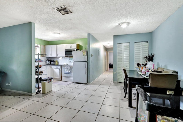 kitchen with visible vents, decorative backsplash, white cabinetry, light tile patterned flooring, and white appliances