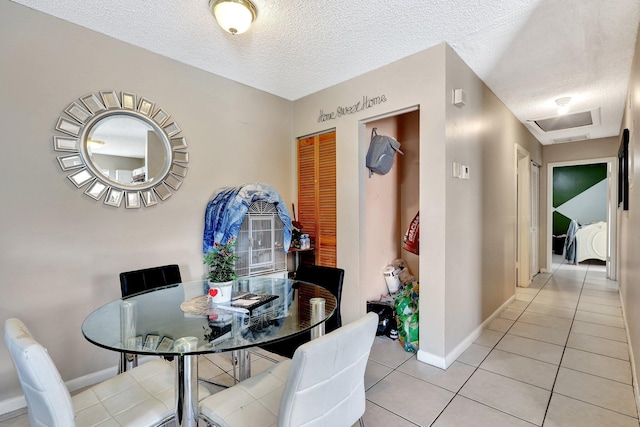 dining room with light tile patterned floors, attic access, baseboards, and a textured ceiling