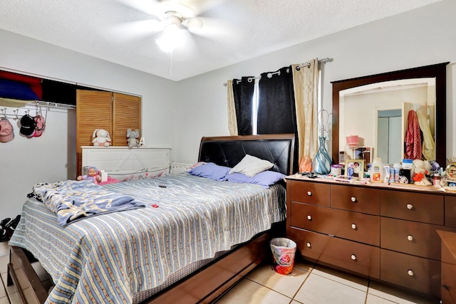 bedroom with a ceiling fan, light tile patterned flooring, and a textured ceiling