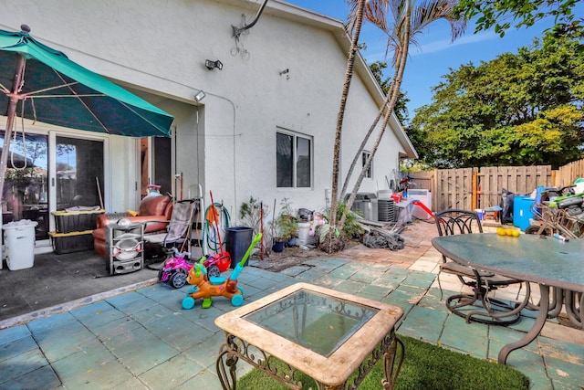 rear view of property featuring a patio, fence, and stucco siding