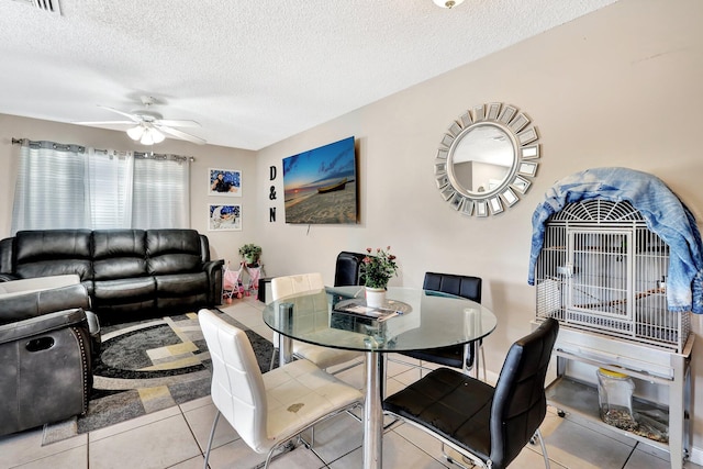 dining space with light tile patterned floors, a textured ceiling, and a ceiling fan