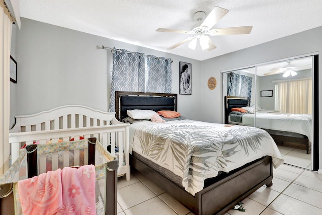 bedroom with a closet, light tile patterned flooring, ceiling fan, and a textured ceiling