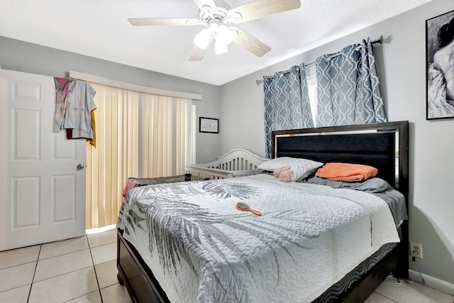 bedroom with a textured ceiling, light tile patterned flooring, and a ceiling fan