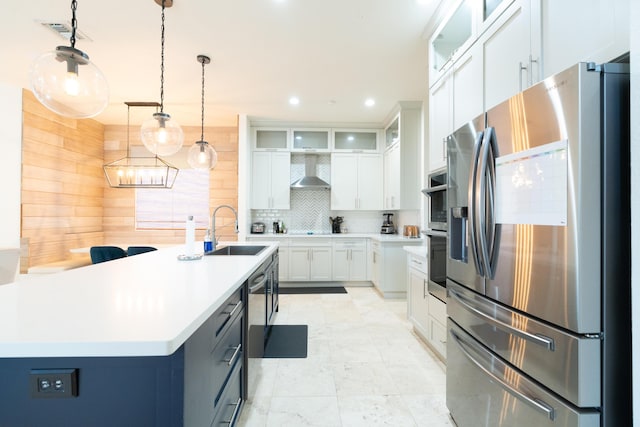 kitchen featuring wall chimney exhaust hood, glass insert cabinets, stainless steel appliances, light countertops, and white cabinetry