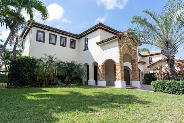 mediterranean / spanish-style home with a front yard, stone siding, and stucco siding