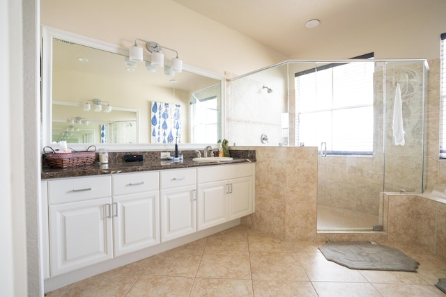 bathroom featuring a stall shower, double vanity, a sink, and tile patterned floors