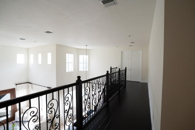 corridor featuring plenty of natural light, visible vents, and dark wood finished floors