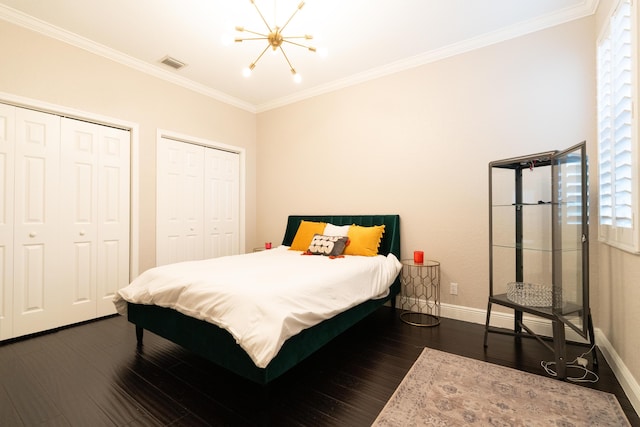 bedroom with ornamental molding, dark wood-style flooring, visible vents, and two closets