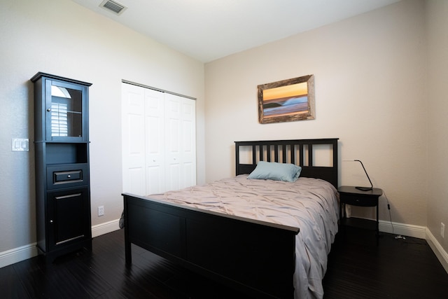 bedroom featuring dark wood-style floors, a closet, visible vents, and baseboards