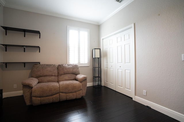 sitting room featuring dark wood finished floors, crown molding, and baseboards