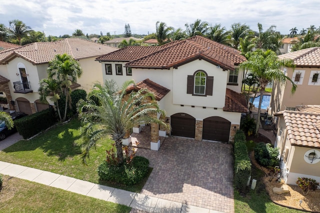 mediterranean / spanish home with stucco siding, a tiled roof, an attached garage, decorative driveway, and a front yard