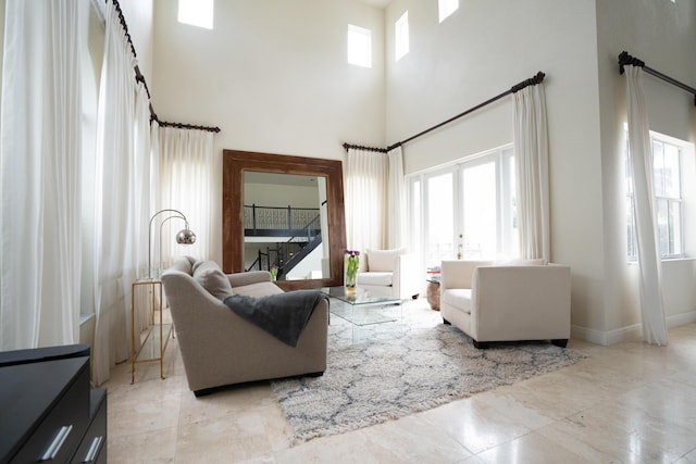 living area with french doors, a towering ceiling, and baseboards