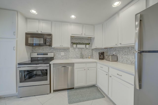 kitchen with stainless steel appliances, white cabinets, light countertops, and decorative backsplash