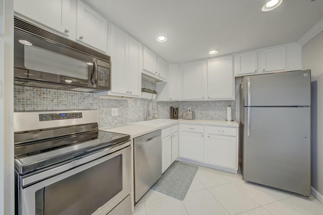 kitchen featuring tasteful backsplash, stainless steel appliances, light countertops, white cabinetry, and a sink