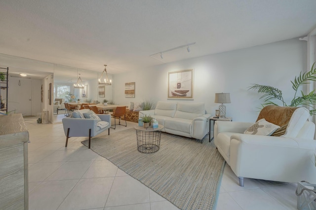 living room featuring a textured ceiling, light tile patterned flooring, a chandelier, and track lighting