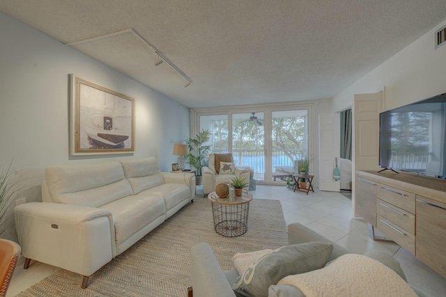 living room with light tile patterned floors, visible vents, a textured ceiling, and rail lighting