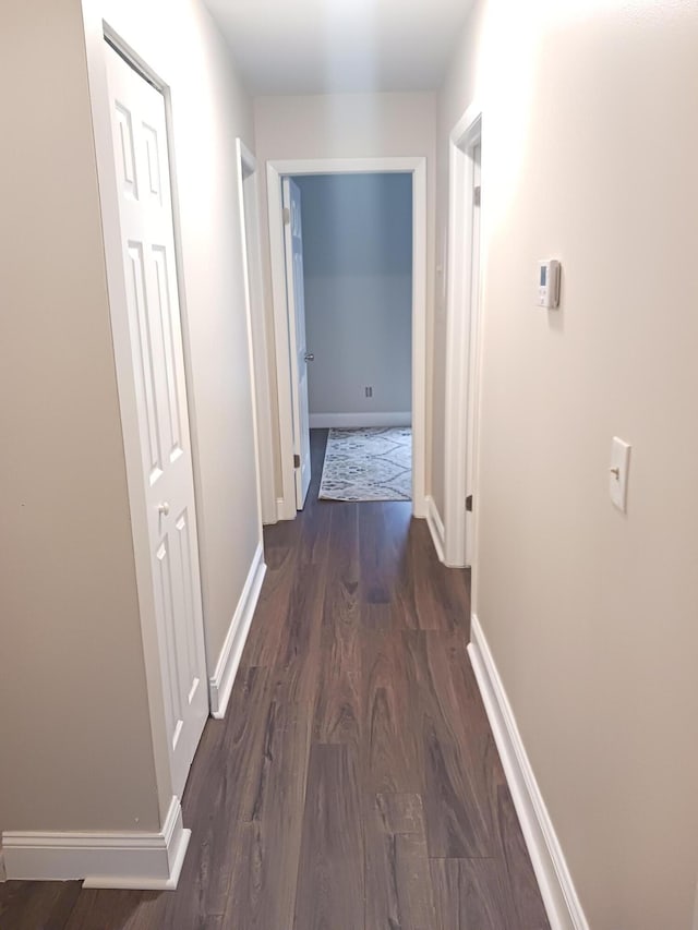 hall featuring dark wood-style floors and baseboards