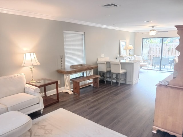 living area with ornamental molding, dark wood finished floors, visible vents, and baseboards