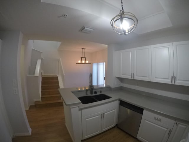 kitchen featuring hanging light fixtures, stainless steel dishwasher, white cabinets, a sink, and a peninsula