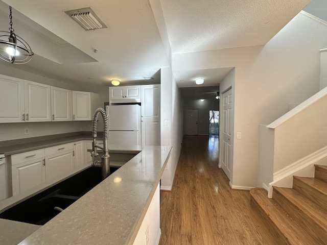 kitchen with visible vents, white cabinetry, freestanding refrigerator, dark countertops, and pendant lighting