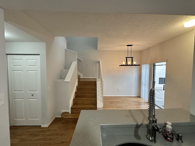 foyer entrance with dark wood finished floors, stairway, a textured ceiling, and an inviting chandelier