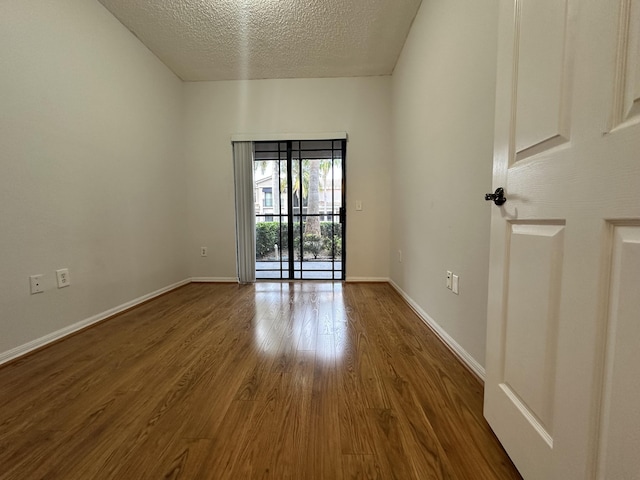 spare room featuring a textured ceiling, baseboards, and wood finished floors