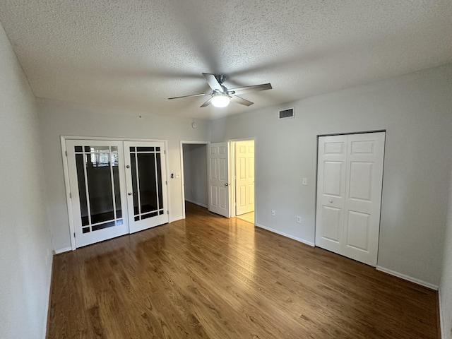 interior space with baseboards, visible vents, wood finished floors, a textured ceiling, and french doors