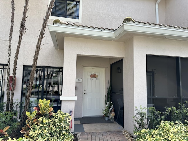 doorway to property featuring a tile roof and stucco siding