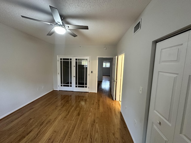 interior space with french doors, dark wood finished floors, a textured ceiling, and baseboards