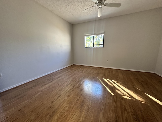 spare room featuring dark wood-style floors, a textured ceiling, a ceiling fan, and baseboards