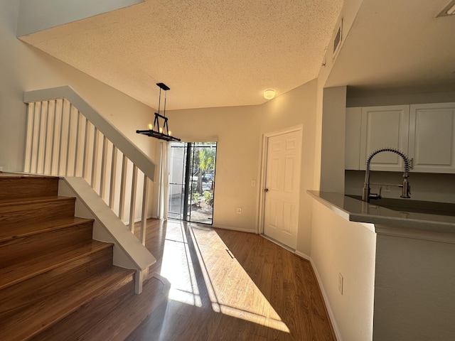 entrance foyer featuring dark wood-type flooring, a textured ceiling, baseboards, and stairs