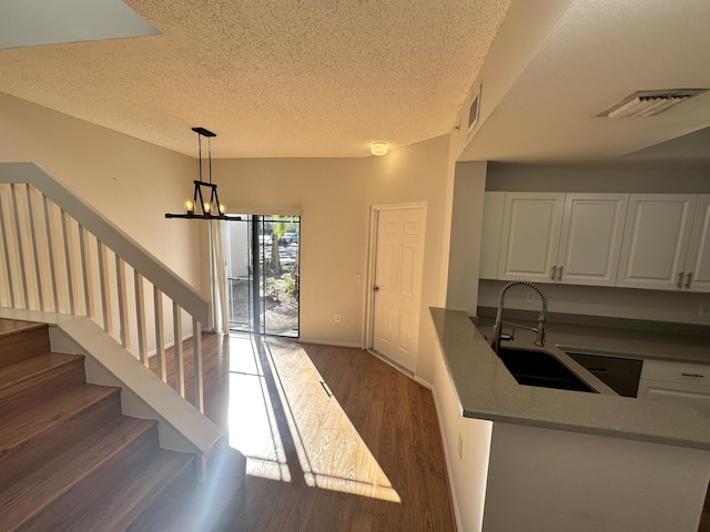 kitchen with a sink, visible vents, white cabinets, dark wood-style floors, and pendant lighting