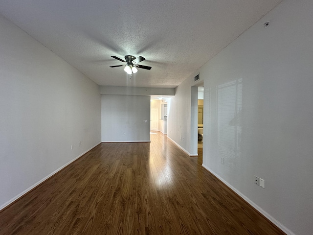 spare room with baseboards, visible vents, dark wood finished floors, ceiling fan, and a textured ceiling