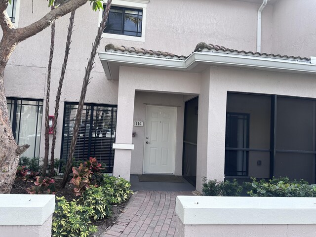 entrance to property featuring a tiled roof and stucco siding