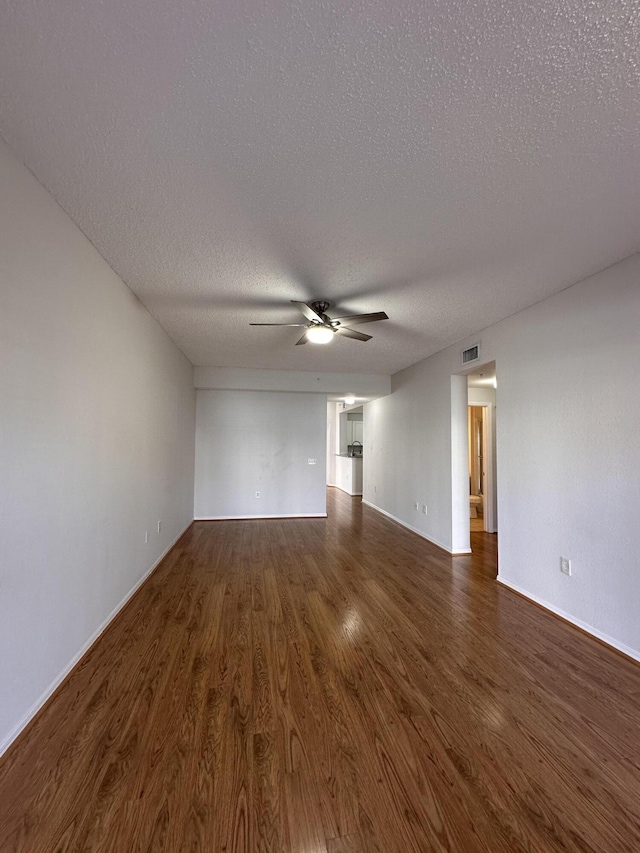 unfurnished living room featuring visible vents, dark wood-style flooring, a textured ceiling, and a ceiling fan